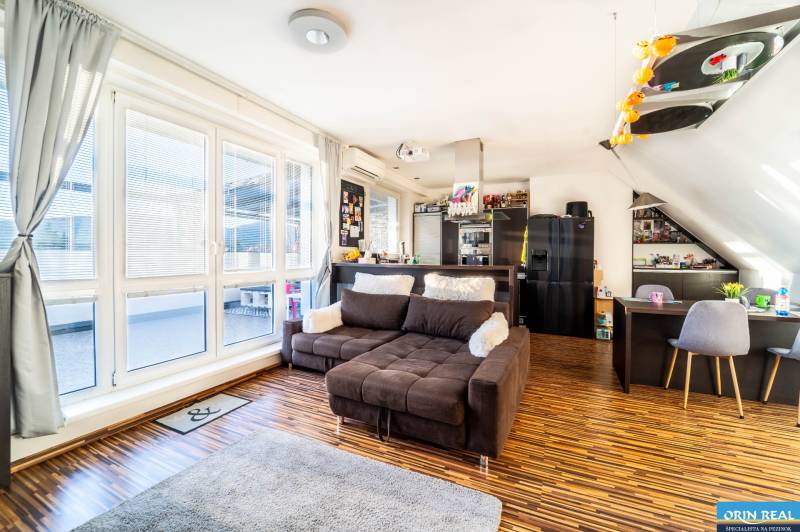 Living room with a comfortable sofa, wooden decor flooring, and large windows in a two-room apartment.