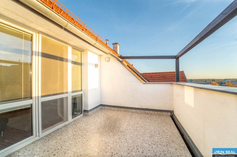 Sunny terrace by a 2-room apartment with a view of the rooftops and the sky.