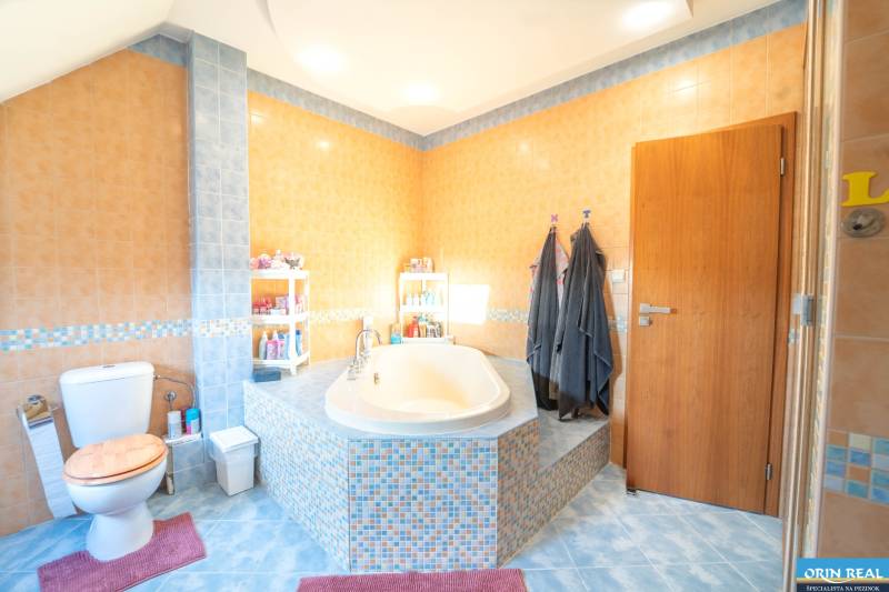 A bathroom with a corner bathtub and colorful tiles in a 2-room apartment.