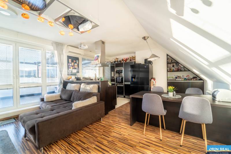 Living room with a kitchen in a 2-room apartment with a wooden decor floor and a comfortable sofa.