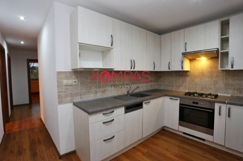 A kitchen with a kitchen unit and a wooden decor floor in a 3-room apartment.