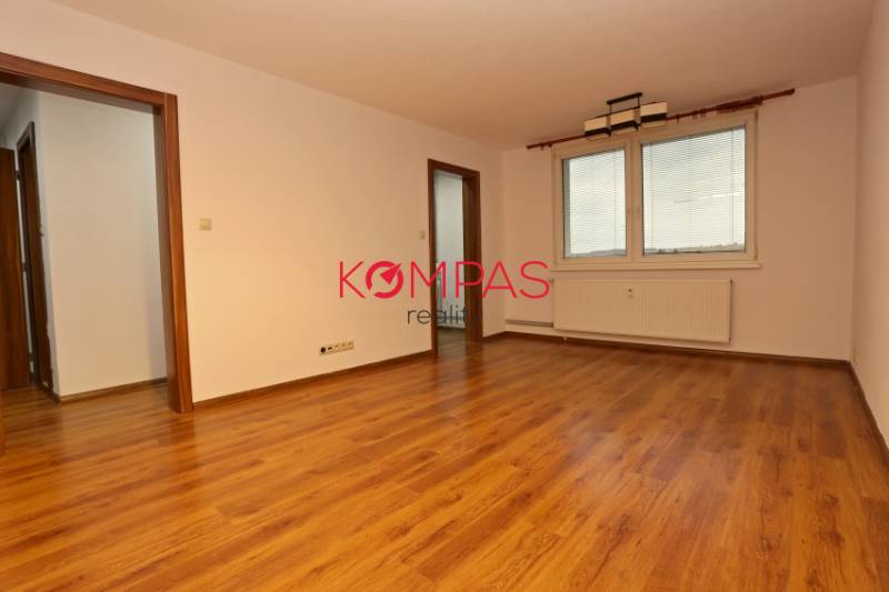 A spacious room with a wooden decor floor and large windows in a 3-room apartment.