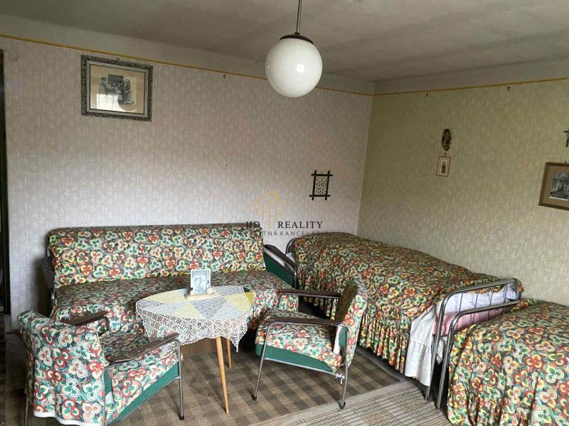 A room in a family house with retro furniture, patterned upholstery, and a carpet.