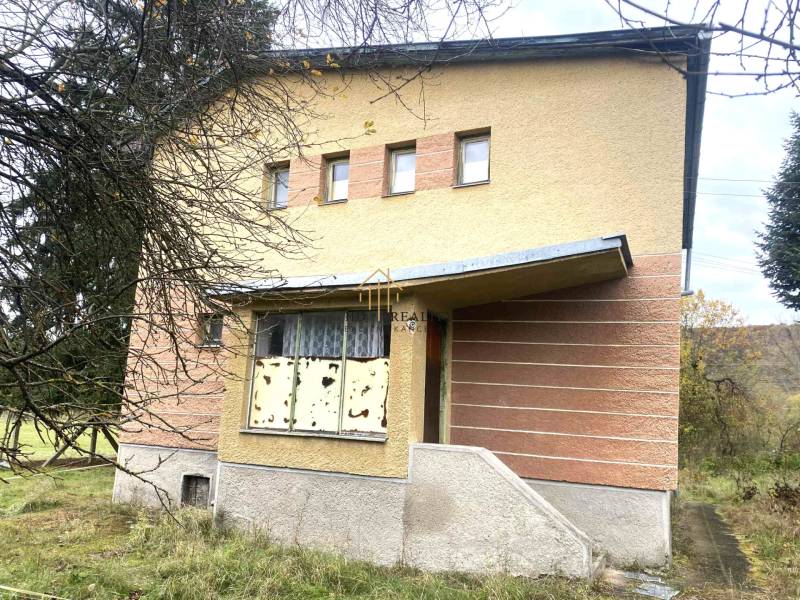 A family house in Rykynčice with colorful plaster, a sloped roof, and shutters.