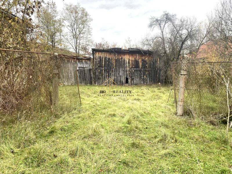 Overgrown plot with a wooden structure near a family house in Rykynčice.