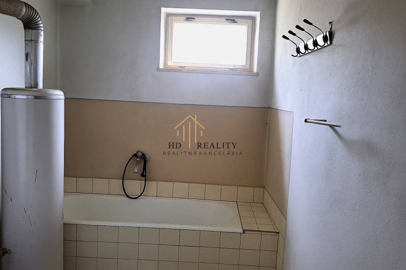 A bathroom in a family house with a bathtub, a window, and a gas heater.