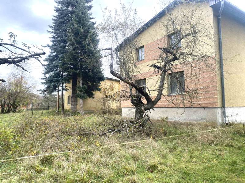 A family house in Rykynčice, surrounded by trees and a grassy garden in the autumn season.
