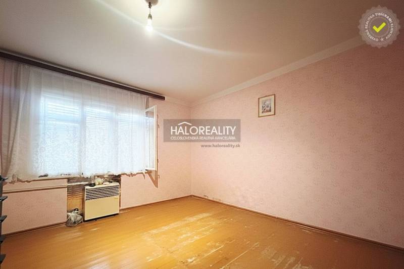 A room in a family house with a wooden decor floor and pink walls.