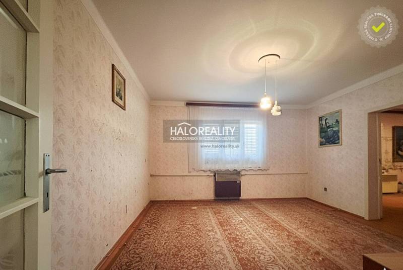 Living room in a family house with carpet, wallpaper, and wall paintings.