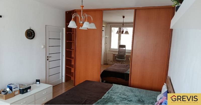 A bedroom in a one-room apartment with a large mirrored wardrobe and a chandelier.
