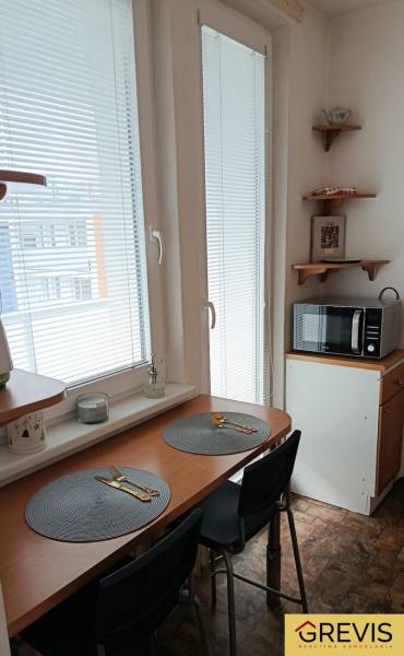 Dining area in a studio apartment with a microwave and a table by the window.