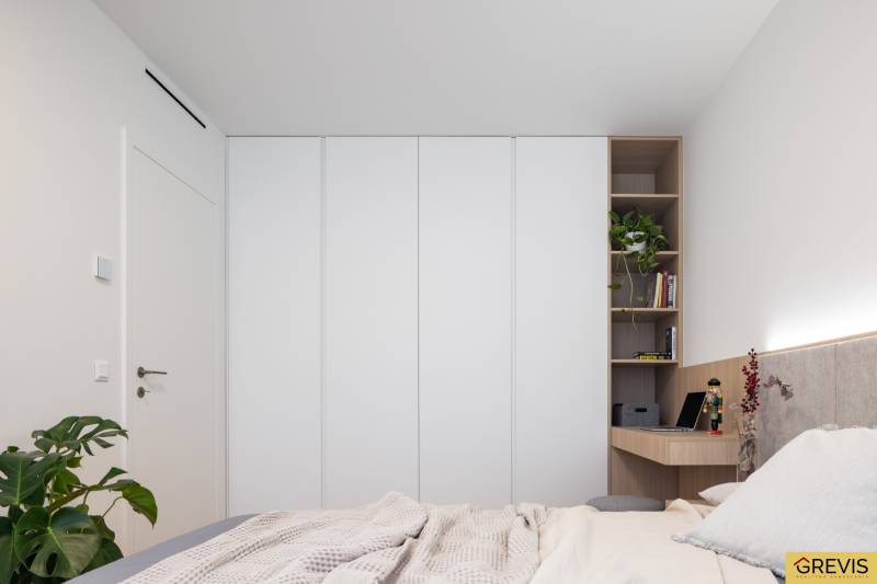 Bedroom in a 3-room apartment with a wardrobe, a plant, and a desk.