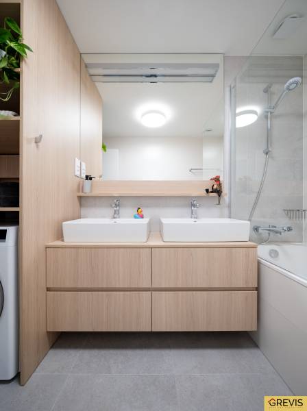 A bathroom in a 3-room apartment with two sinks, a mirror, and a bathtub.