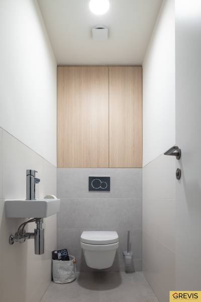 A bathroom with a ceramic sink, gray tiles, and a floor with a wood decor in a 3-room apartment.