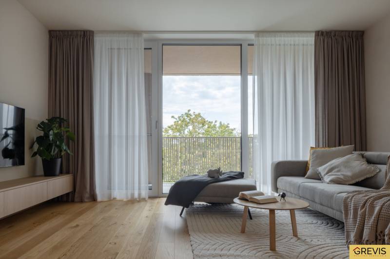 Living room with a sofa, wooden decor flooring, and a large window in a 3-room apartment.