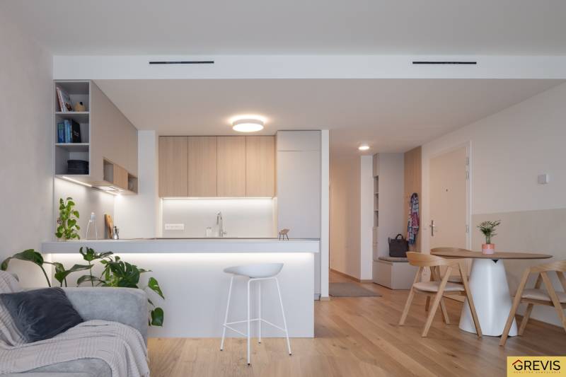 A kitchen in a 3-room apartment with a bar counter and plants, floor with wooden decor.