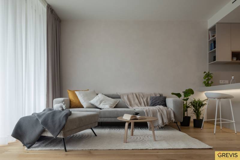 Living room in a 3-room apartment with a sofa, table, plants, and a floor with a wooden decor.