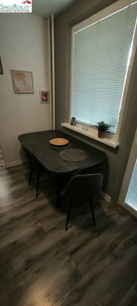 Dining area in a 3-room apartment with a wooden decor floor, with simple furnishings.