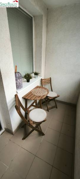 A balcony with wooden furniture and tiles in a 3-room apartment.