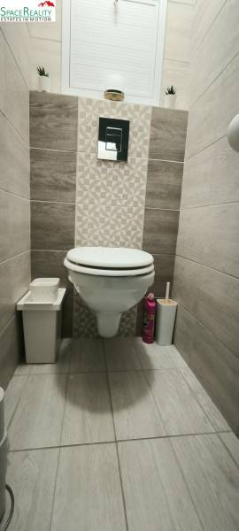 The toilet with tiles in the 3-room apartment has a floor with a wooden decor.