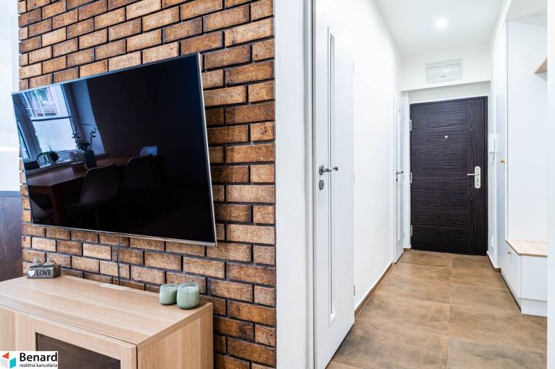 TV on a brick wall and entrance hallway in a 3-room apartment.