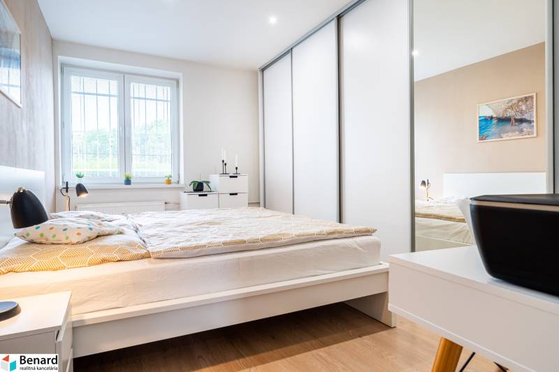 Bedroom in a 3-room apartment with wood-patterned flooring and white furniture.