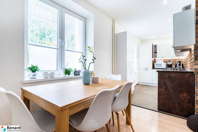 Dining area with a table and plants in a 3-room apartment with a kitchen.