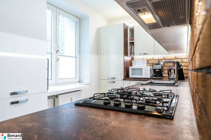 A kitchen in a 3-room apartment with white cabinets and a kitchen counter with brick cladding.