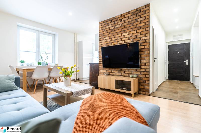 Living room with a sofa, table, and TV, in a 3-room apartment. Floor with wooden decor.