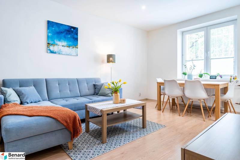 Living room in a three-room apartment with a sofa and a dining table, floor with wood decor.