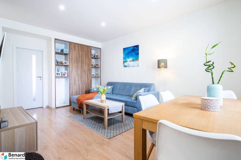 Living room in a 3-room apartment with a blue sofa and a wooden decor floor.