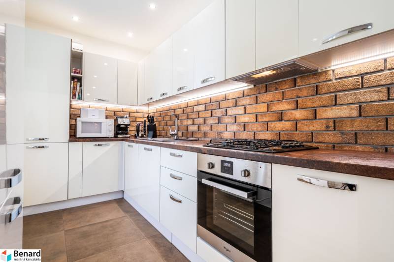 A kitchen in a 3-room apartment, with a brick wall and modern appliances.