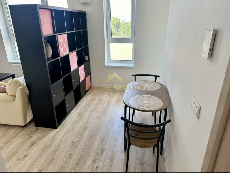 Dining area with wood-patterned flooring and a shelf in a 2-room apartment.