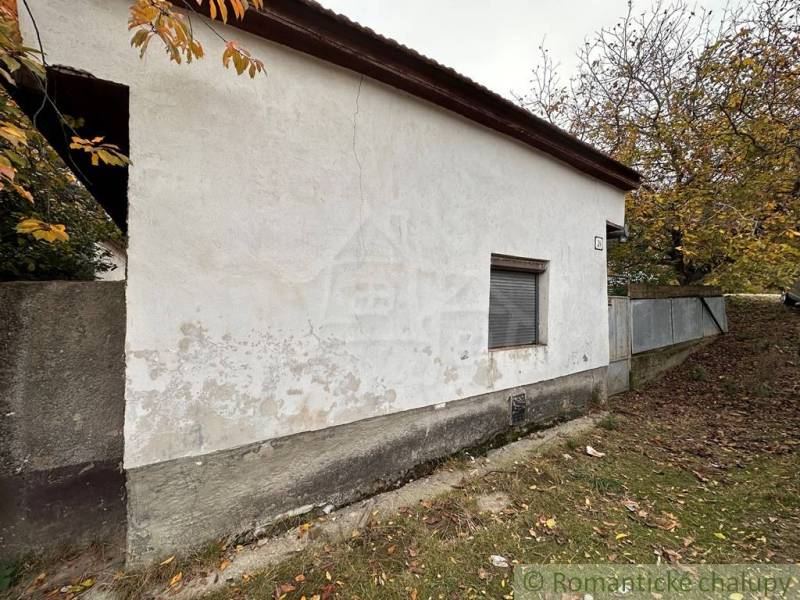 A family house in Zemné with a plastered facade, surrounded by autumn trees and grass.