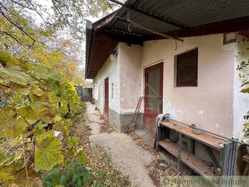 The exterior of a family house in Zemné with old plaster and a shelter.
