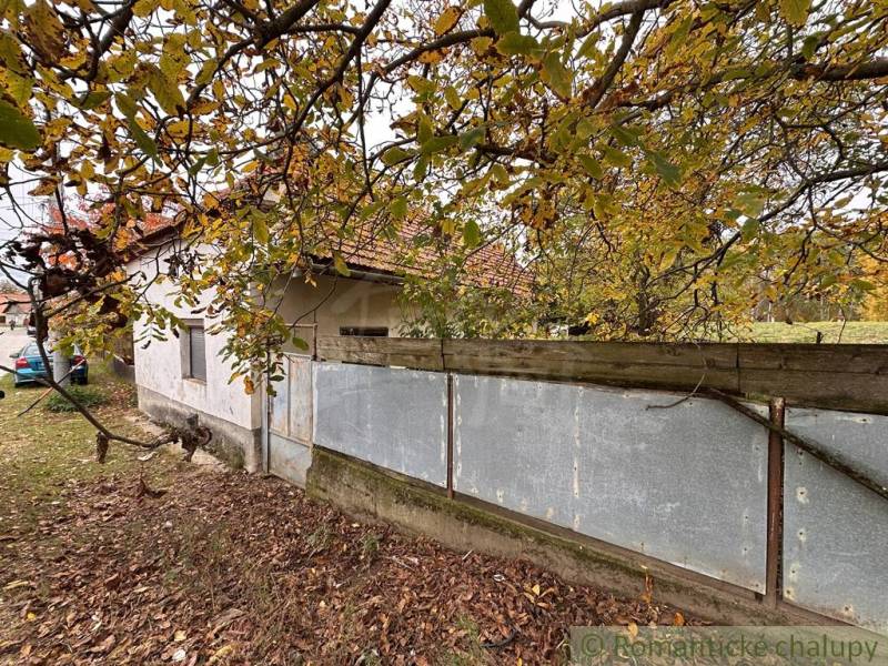 A family house in Zemné with an older fenced garden and colorful leaves on the trees.