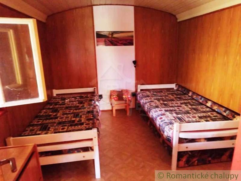 Wooden interior of a cabin with two beds and a floor with a wooden decor.