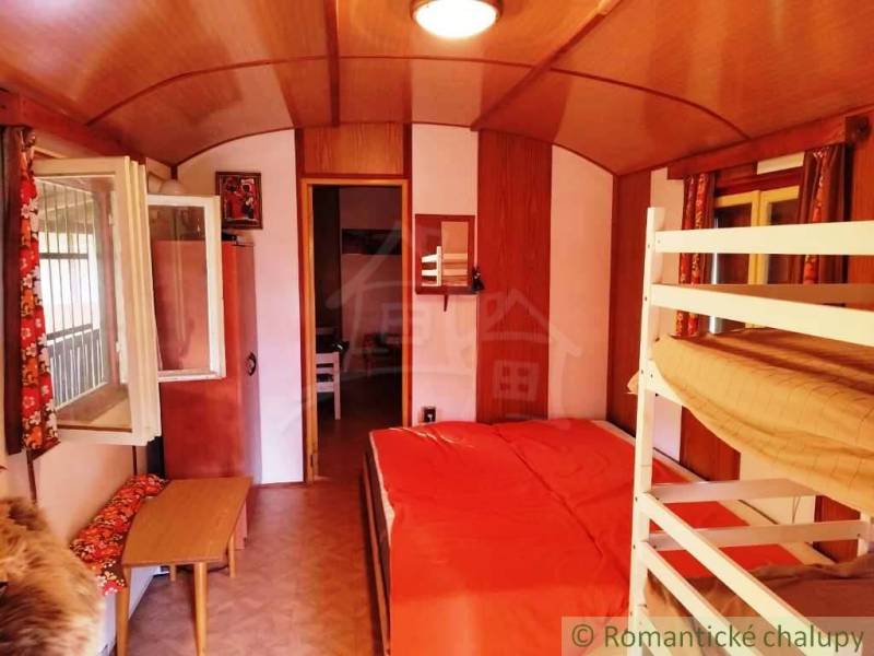 The interior of a cabin with a bunk bed, a wood-patterned floor, and an open window.