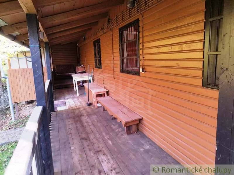 A cottage in Dudince with a veranda featuring a wooden decor floor and a bench.