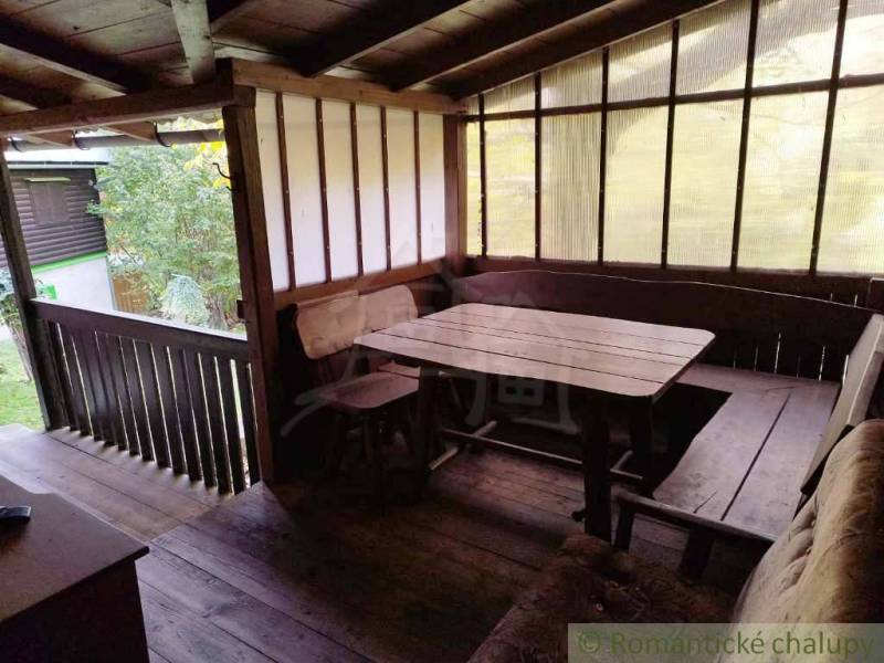 Covered terrace at the cottage with wooden decor and wooden seating.