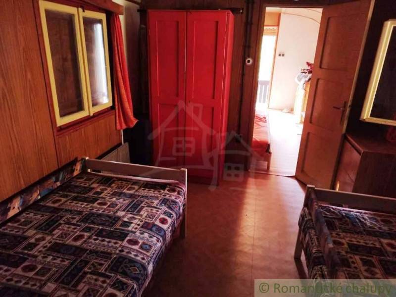 The interior of a cabin with two beds, a red wardrobe, and a carpet with a geometric pattern.