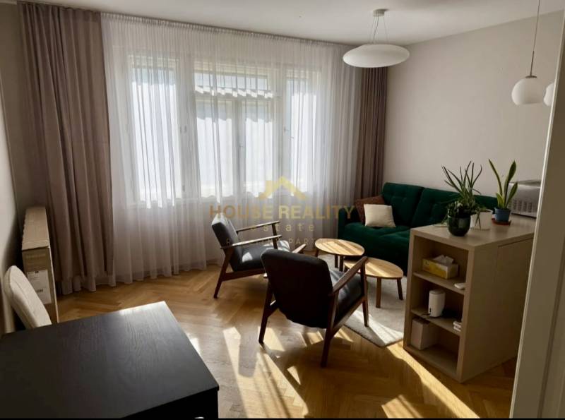 Living room in a 3-room apartment with a wooden decor floor, green sofa, wooden chairs.