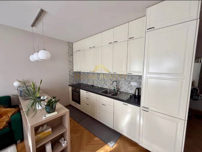 A kitchen in a 3-room apartment with white cabinets and a wooden decor floor.