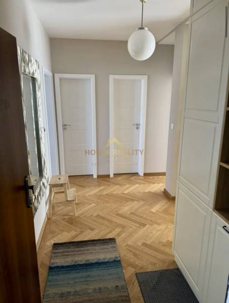 A hallway in a 3-room apartment with a wooden decor floor, white doors, and a rug.