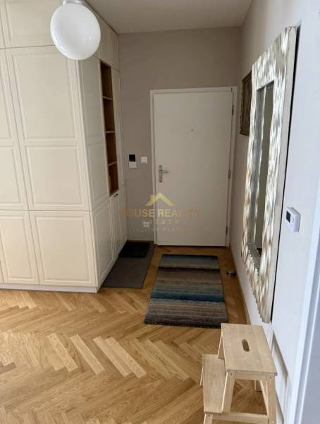 Entrance hall in a 3-room apartment with wood-patterned flooring and white furniture.