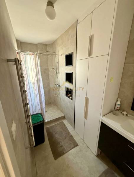 A bathroom in a 3-room apartment with a shower, cabinets, and beige walls.