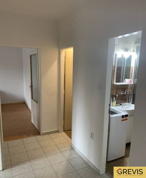 A hallway in a 2-room apartment with access to the bathroom and a room with flooring.