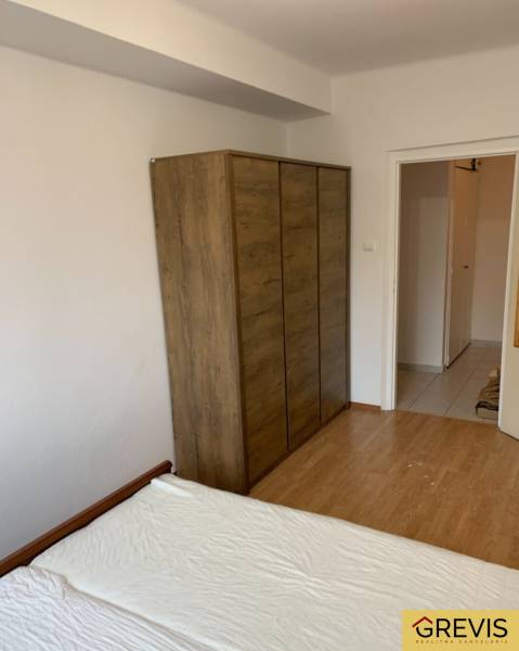Bedroom in a 2-room apartment with a bed, wardrobe, and floor with a wooden decor.