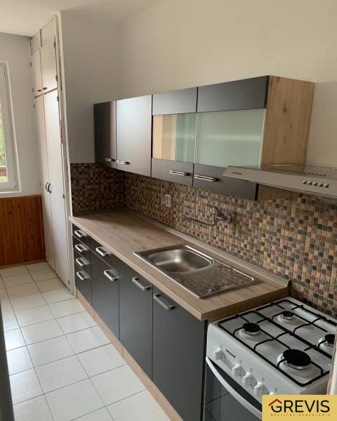 A kitchen in a 2-room apartment with mosaic tiles and a floor with a wooden decor.