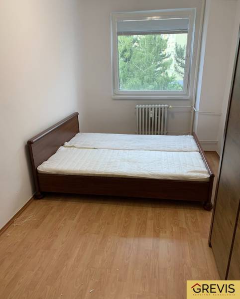 Bedroom in a 2-room apartment with a wooden decor floor and a double bed.